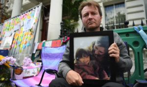 SITTING — Richard Ratcliffe sits outside the Iranian Embassy in London holding a photo of his wife and daughter as he starts a hunger strike.