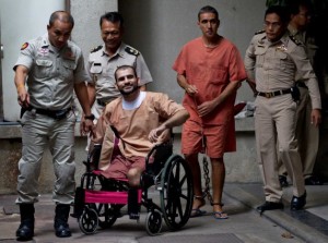 OFF TO PRISON — Thai police lead the Bangkok bombers out of the courtroom after Saeid Moradi (in wheelchair) was given life imprisonment and Mohammad Khazai (behind Moradi in chains) was sentenced to 15 years.