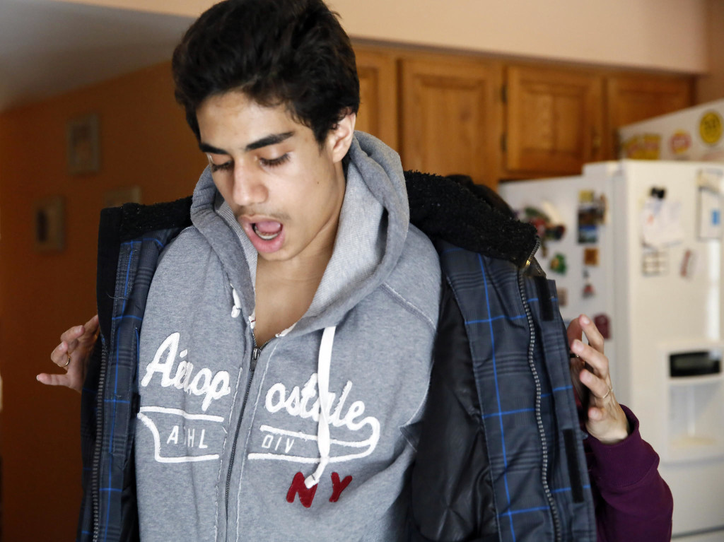 OUCH—Omid Babakhani winces as his mother helps him on with his coat over broken collar bones.