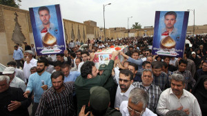FUNERAL — Mourners carry the coffion of the Iranian pilot (pictured on the poster) reported killed last week fighting in Samara, Iraq.