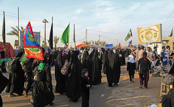 A group of Iranian pilgrims with flags and banners is walking to Karbala.
