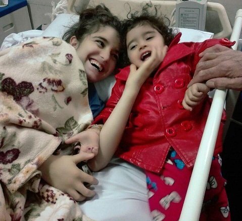 RESCUE — Three-year-old Hoda Yazdan-Shenas (right) visits in bed with her big sister, 13-year-old Haniyeh, who rescued the little girl from their collapsing house during the November earthquake in Kermanshah province. The older girl suffered spinal damage.