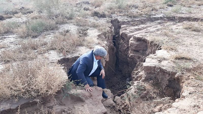 SINKING — A staffer from the Tehran Building and Housing Research Center checks out a fissure that has opened up to the west of Tehran because there is no longer enough water below to hold up the surface of the province.