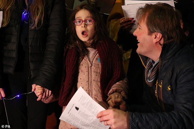 CAROLING — Richard Ratcliffe watches his daughter, Gabriella, hit the high notes as they sing Christmas carols outside #10 Downing Street.