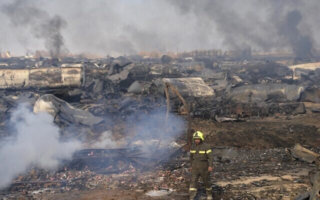 The charred mass of hundreds of trucks is seen after the fire died down.  At bottom, a satellite photo shows the extent of the fire.