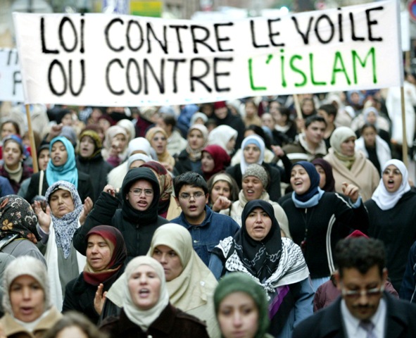 PROTEST — Muslims in France protest under a sign saying, “Law against the veil, or against Islam.”