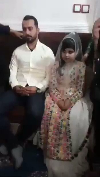 BABY-FACED A decidedly young bride sits beside her new husband at a wedding ceremony.