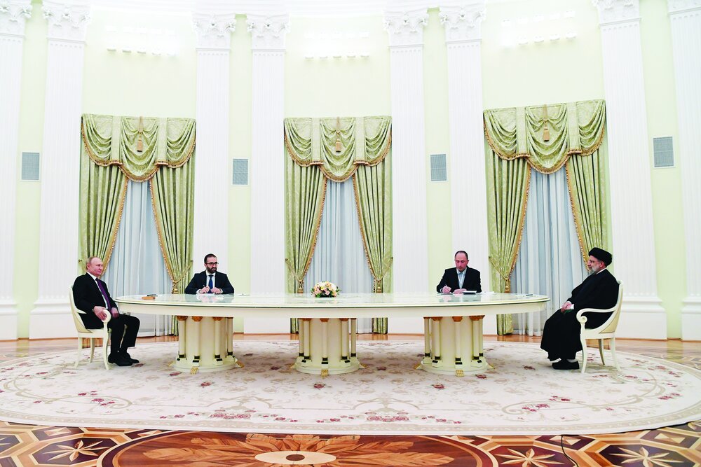 SUMMIT — Russian President Vladimir Putin (far, far left) talks with Iranian President Ebrahim Raisi (far, far right) at an unusual table in the Kremlin.