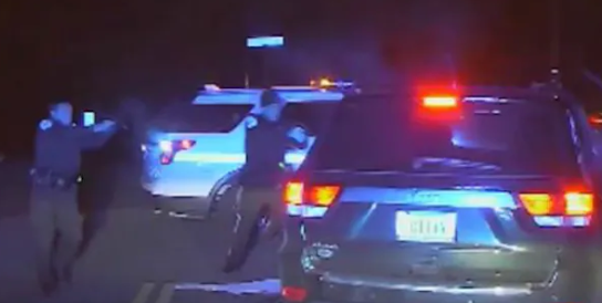 DEATH SCENE – In this still shot extracted from a police video, two park police officers are seen shooting into the car being driven slowly forward by Bijan Ghaisar, 25, some 4-1/2 years ago. The two officers said they had to fire because Ghaisar was driving the car at officer Alejandro Amaya (near the center of this photo). Some who have watched the video say Amaya was to the side of Ghaisar’s car, not in front of it, and in no danger.