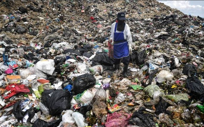 SMELLY — A villager walks through a mountain of trash as tall as a football field is long that has been festering (and growing) ever since the revolution.