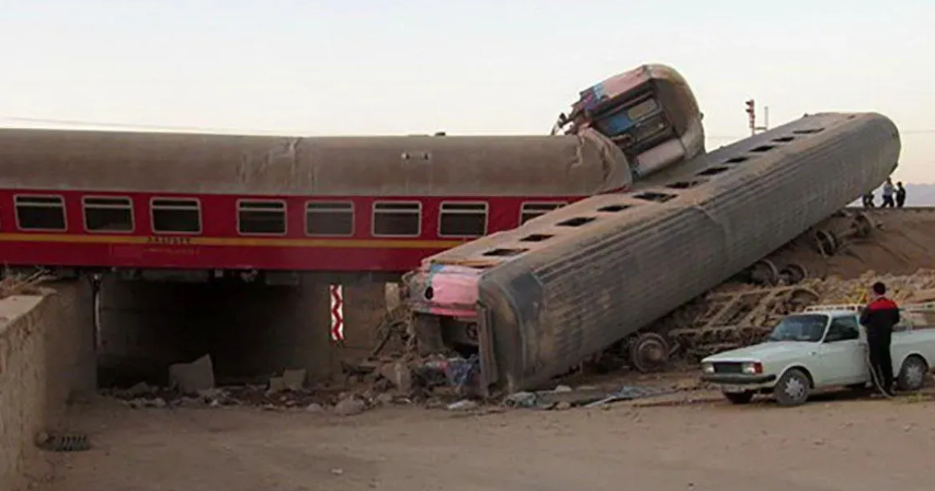 DERAILED — Three of the derailed cars can be seen at left. Above, the excavator was knocked over and ended up with its tracks pinned to the side of a car that was not derailed. Below, a railway map pinpoints the site of the derailment near Tabas