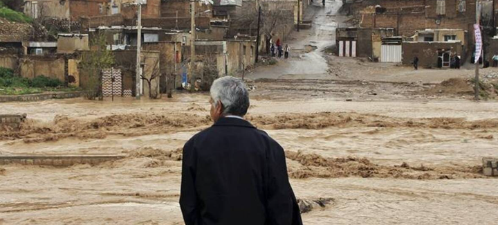 WET — A resident of Estahban watches helplessly as rainwater races through the streets of the city.